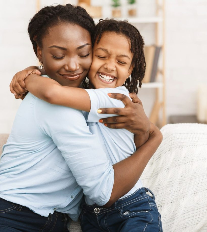 Happy black family hugging and embracing on couch